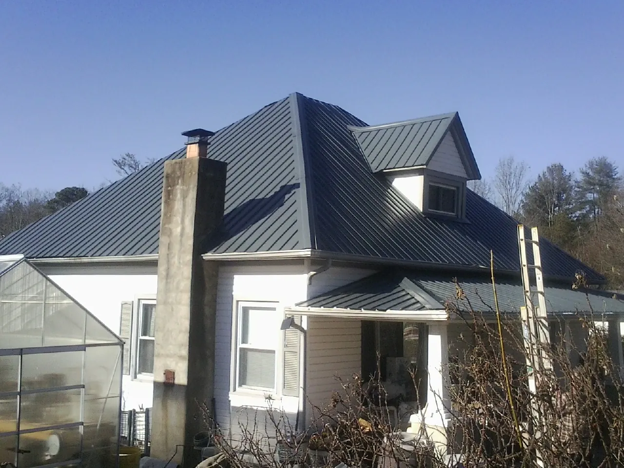 Dark blue standing seam metal roof on a white farmhouse with dormer — Slate & Tile Roof Repair by Roofing Brothers in Port Costa