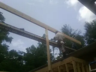 Carpenter setting a ridge beam over a new addition frame — Ice Dam Removal by Roofing Brothers in Port Costa