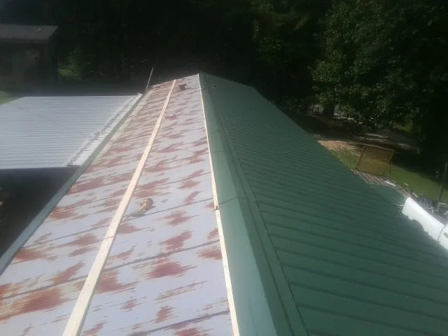 Old rusted panels beside newly installed green metal roofing — Wind Damage Roof Repair by Roofing Brothers in Port Costa