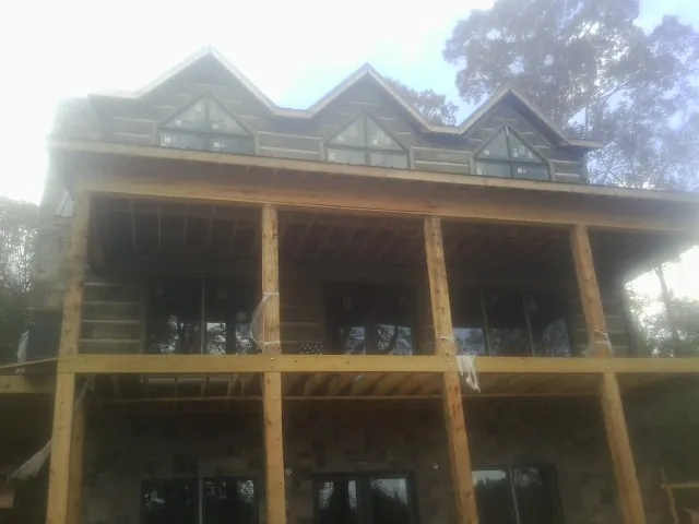 Dormers and porch framing on a large log home under construction — Roof Coating work by our crew in Port Costa