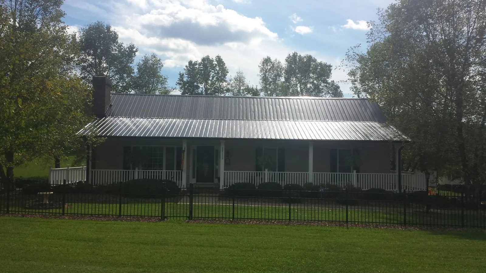 Gray metal roof on a brick ranch with a full width front porch — Gutter Guard Installation work by our crew in Port Costa