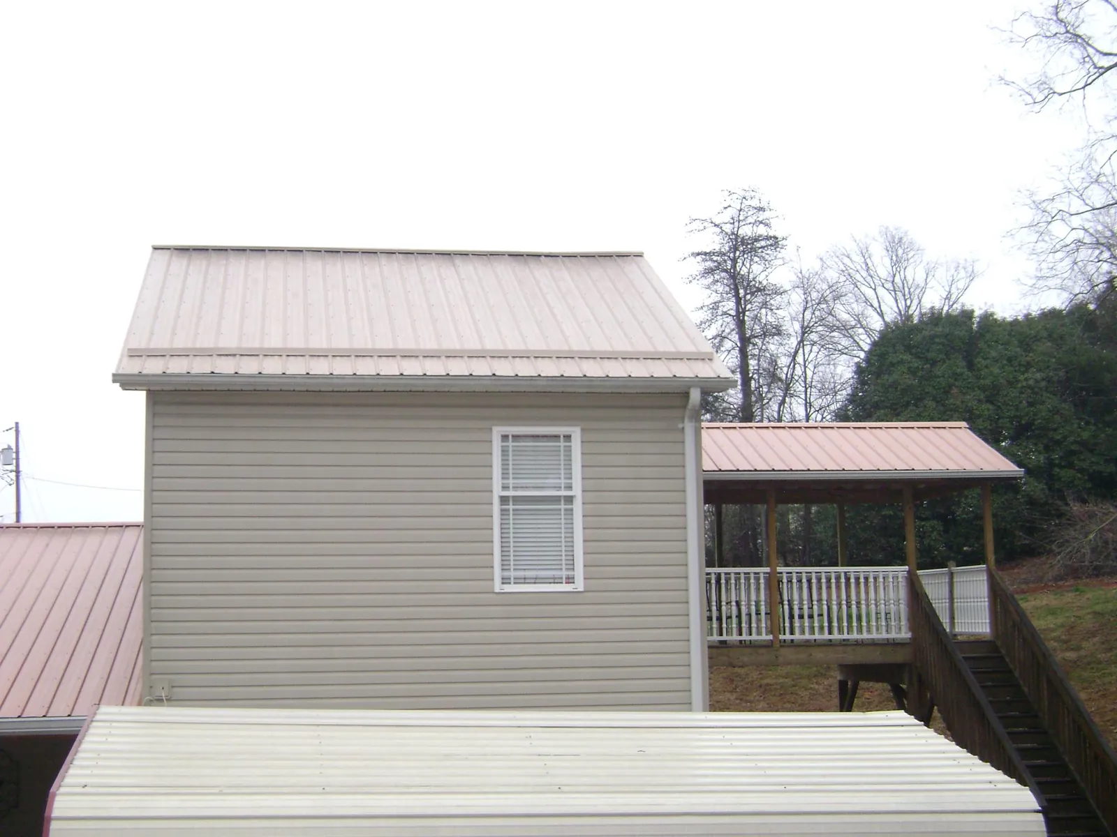 Tan metal roofs on a two story addition and attached porch, from a Roof Replacement job in Port Costa