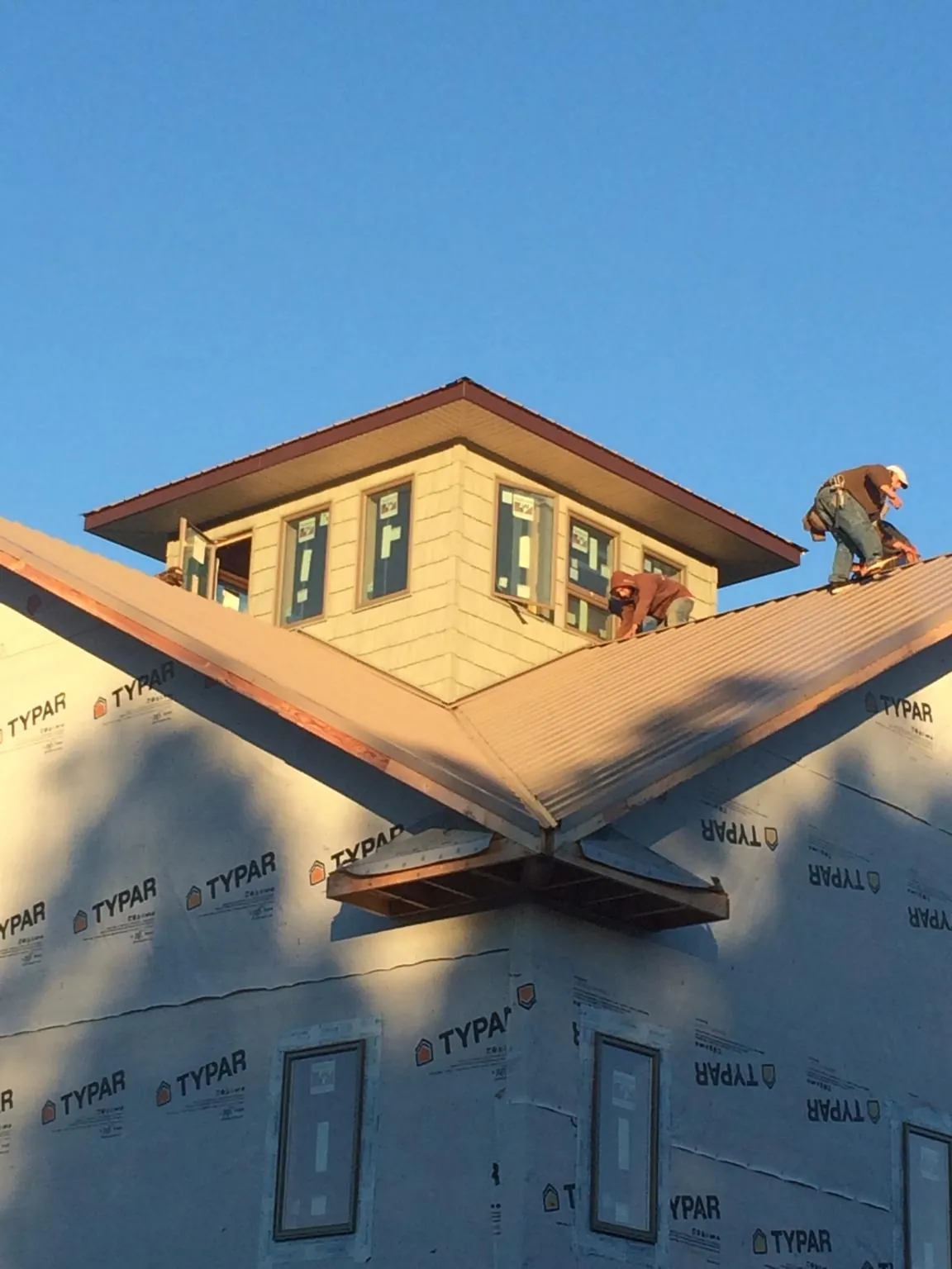 Roofers working around a rooftop cupola on a new metal roof at sunset — Roof Waterproofing in Port Costa by Roofing Brothers